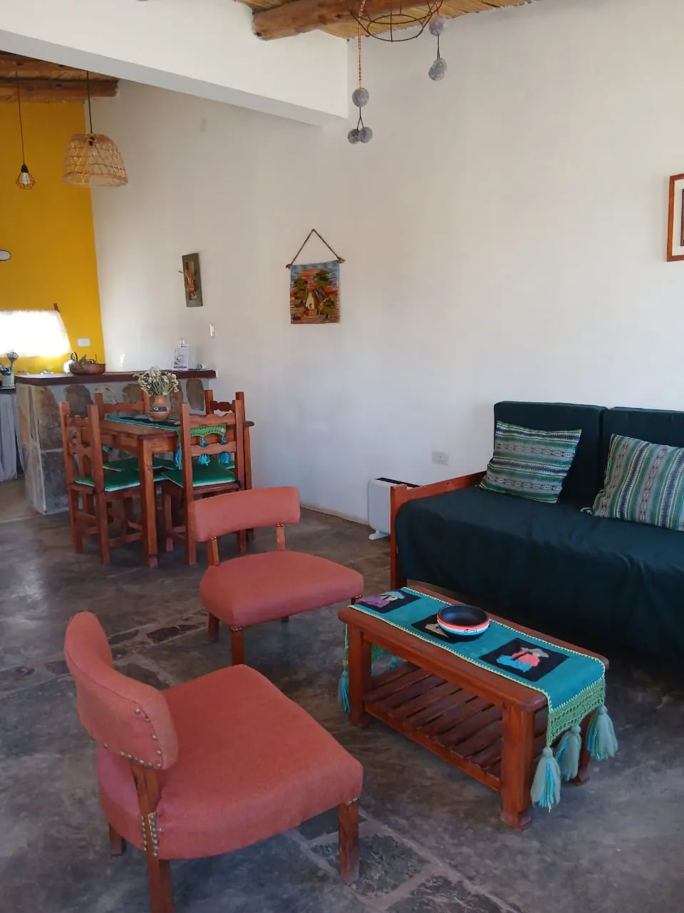 Cabaña Tierra: living con sillón verde, sillones terracota y cocina integrada al fondo
