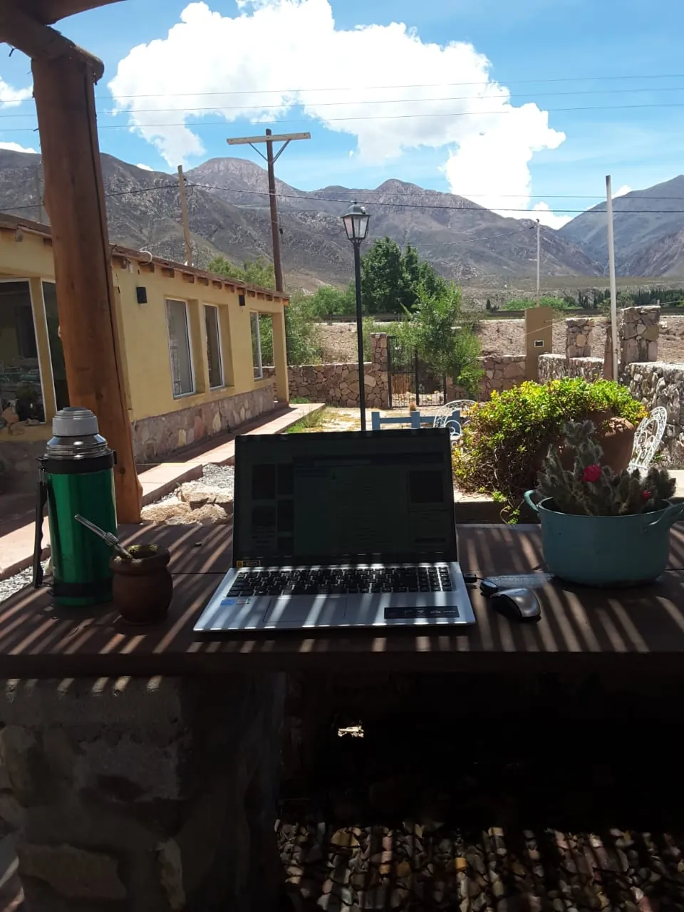 Notebook y termo sobre la mesa de la galería, con los cerros de fondo
